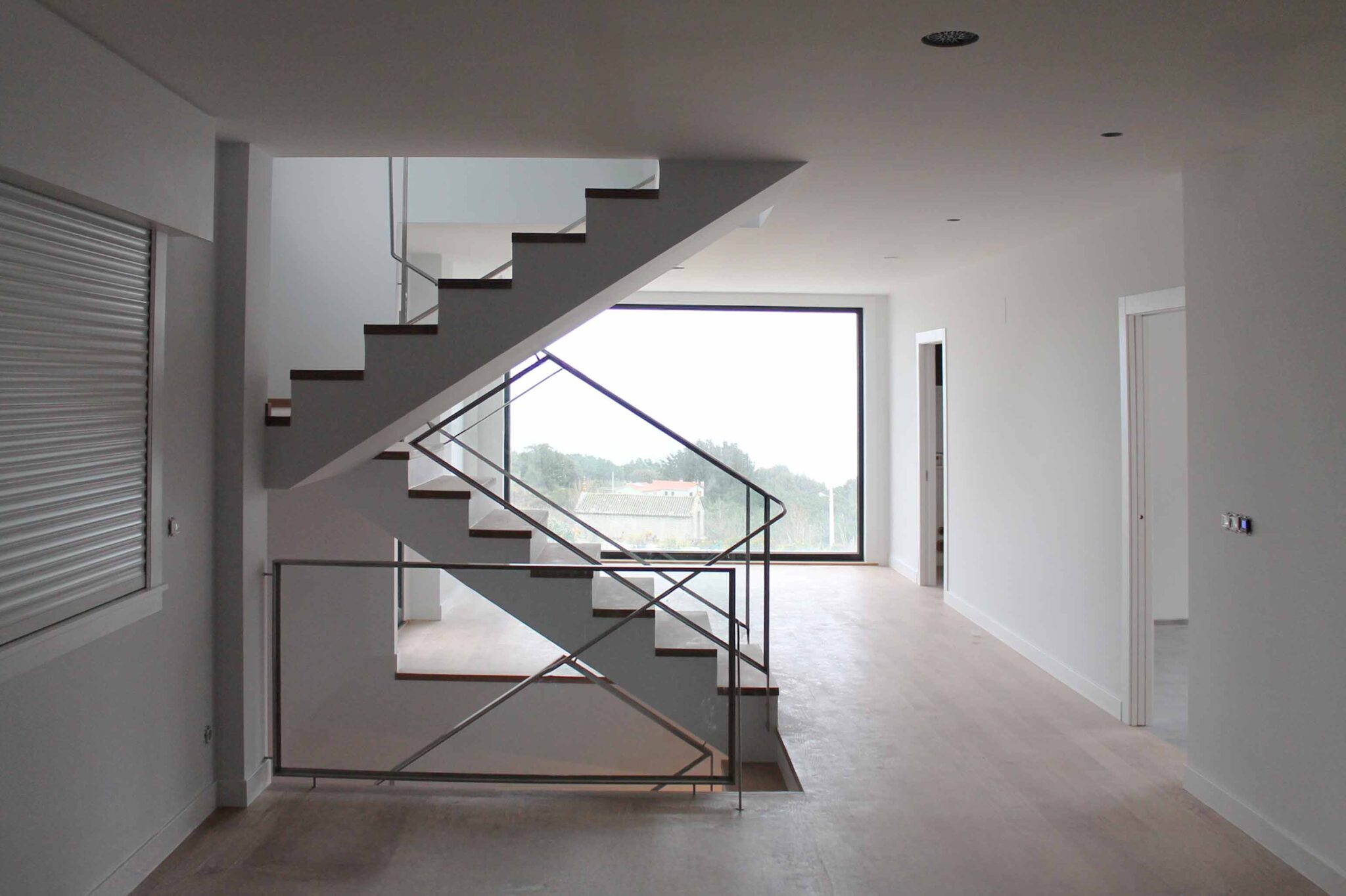 Proyectos destacados. Interior de vivienda unifamiliar de obra nueva con escalera de diseño moderno y barandilla de cristal. Escalera contemporánea, diseño de interiores, vivienda minimalista, arquitectura residencial.